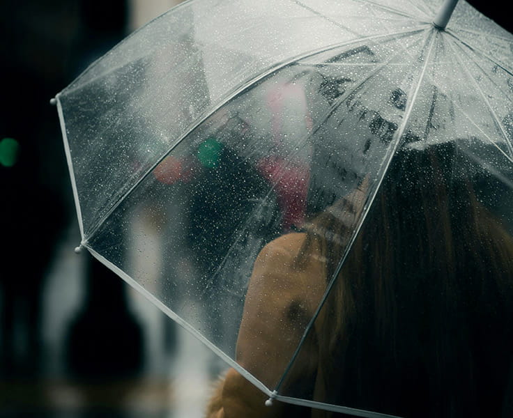 woman standing in the rain with an umbrella